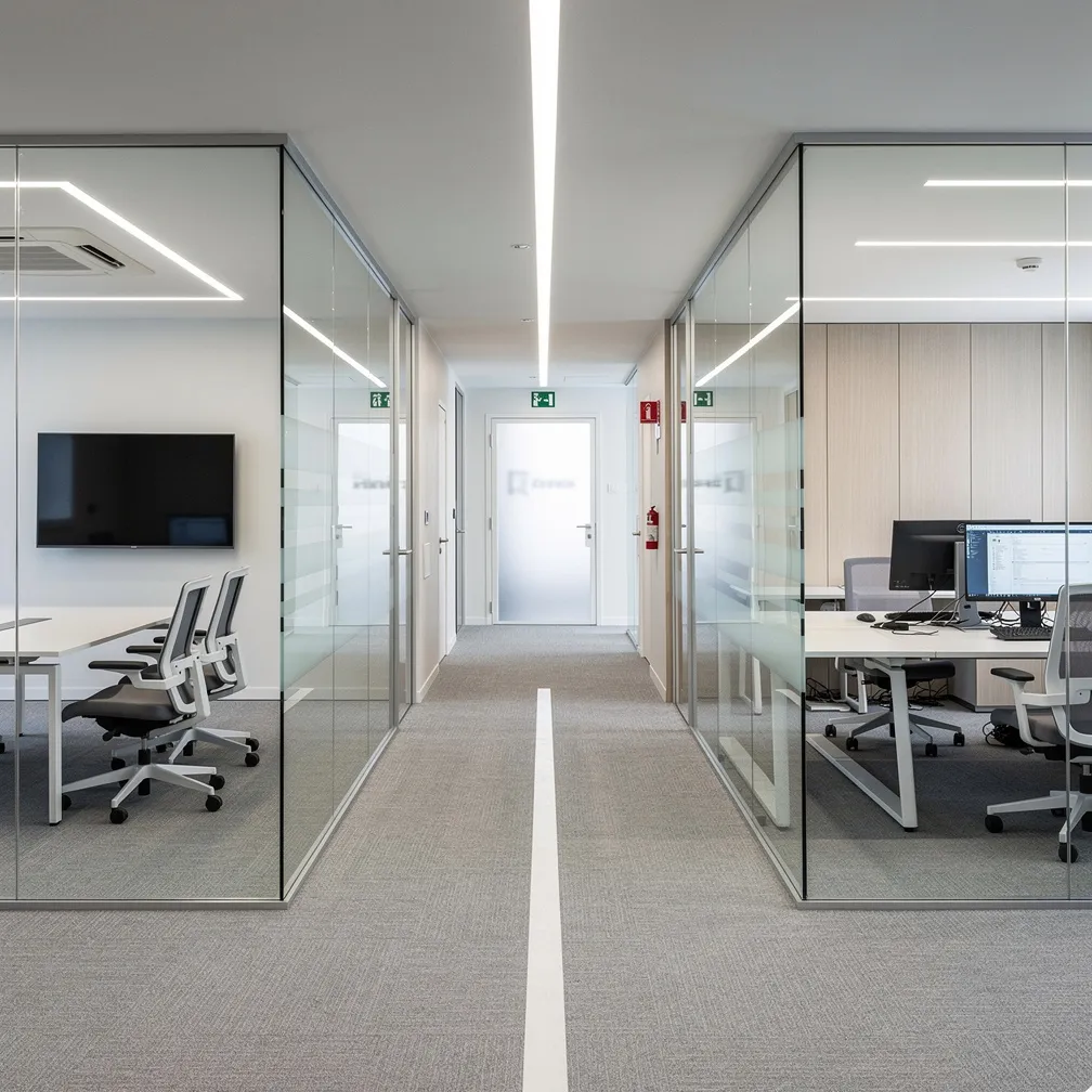 Ufficio riconfigurato con pareti mobili vetrate, corridoio e uscita di emergenza in vista